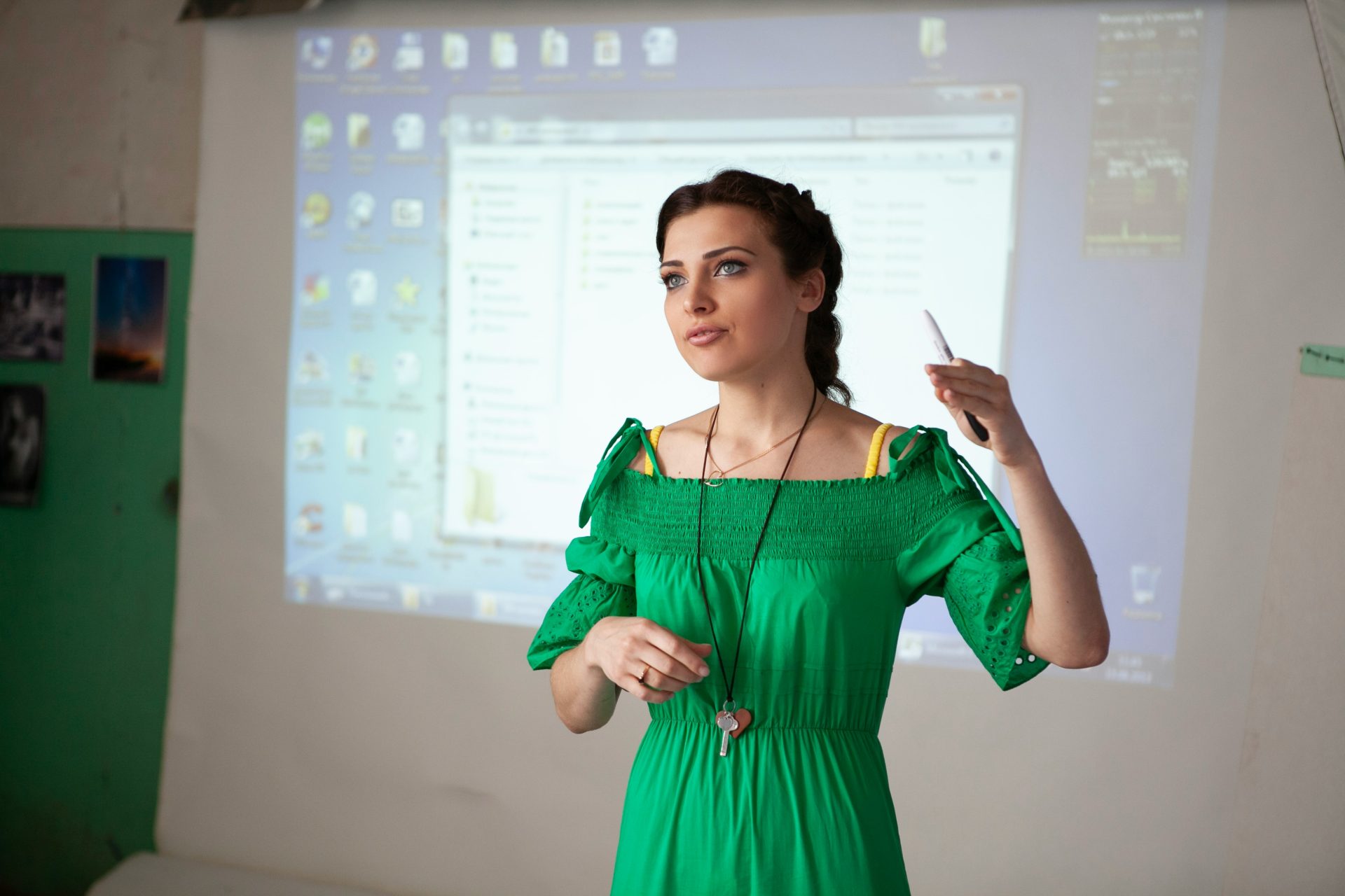 Woman in green dress presenting with projector screen projection screen.