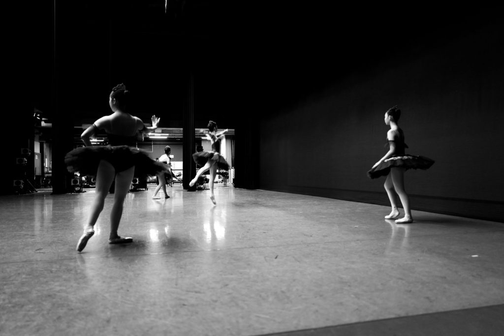 Young ballerinas practice in a dark studio